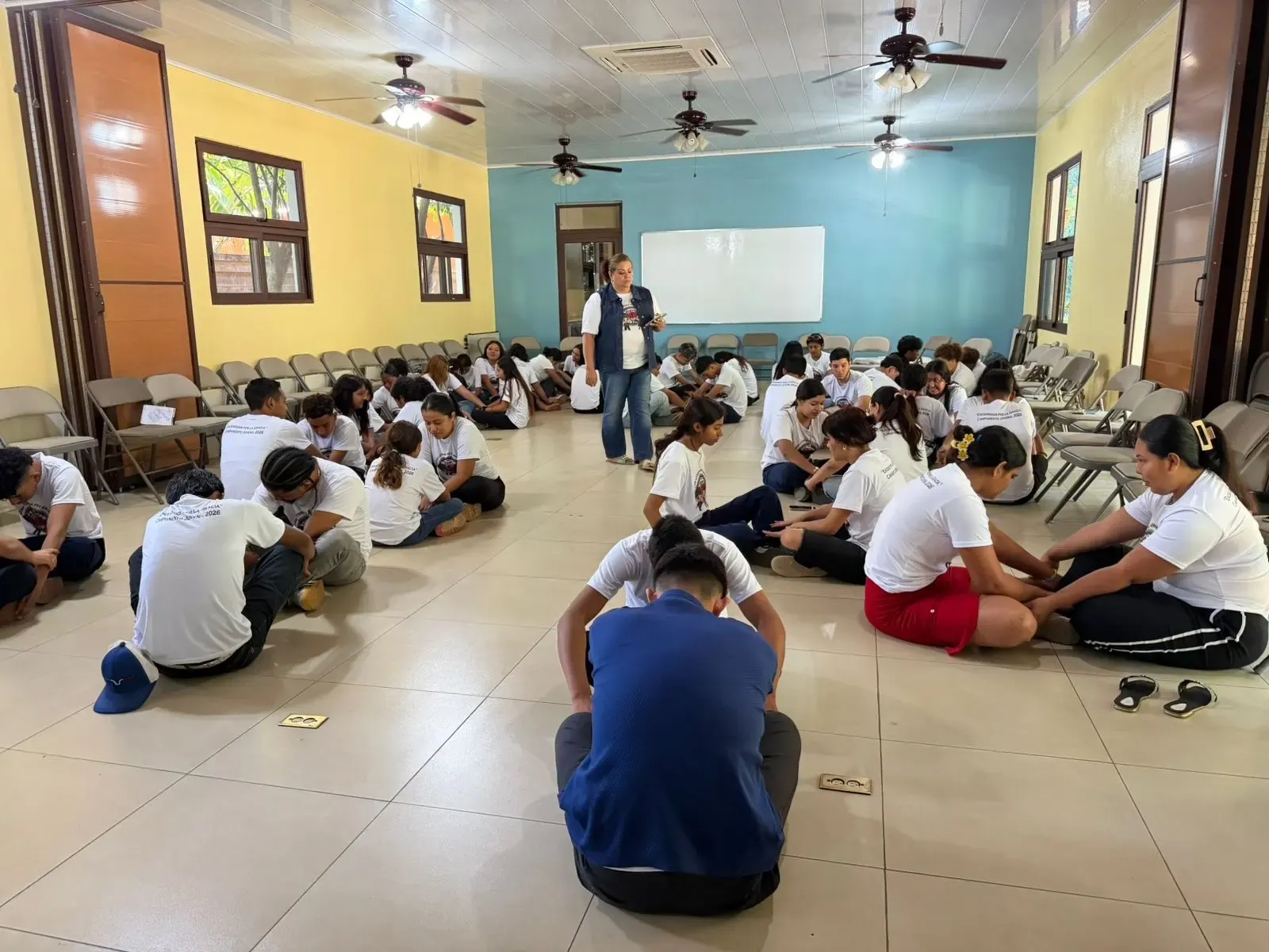 Varios jóvenes sentados en el suelo participan en una actividad comunitaria.